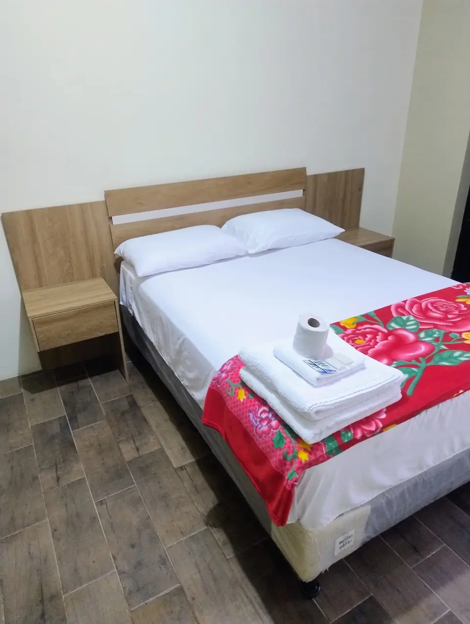 Cama matrimonial con toallas y cobija de colores