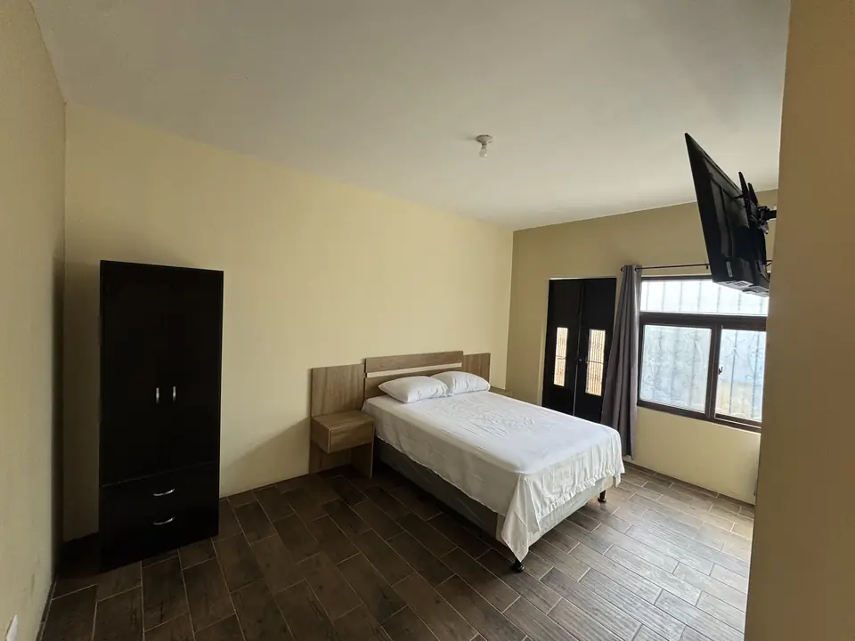 Habitación con cama matrimonial, ropero, TV y ventana